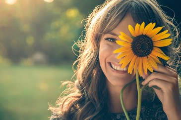 Frau mit Sonnenblume vor dem linken Auge
