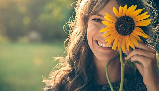 Frau mit Sonnenblume vor dem linken Auge
