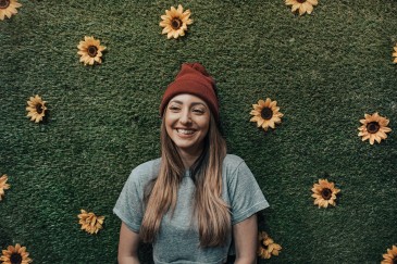 Frau vor grüner Wiese mit Sonnenblumen